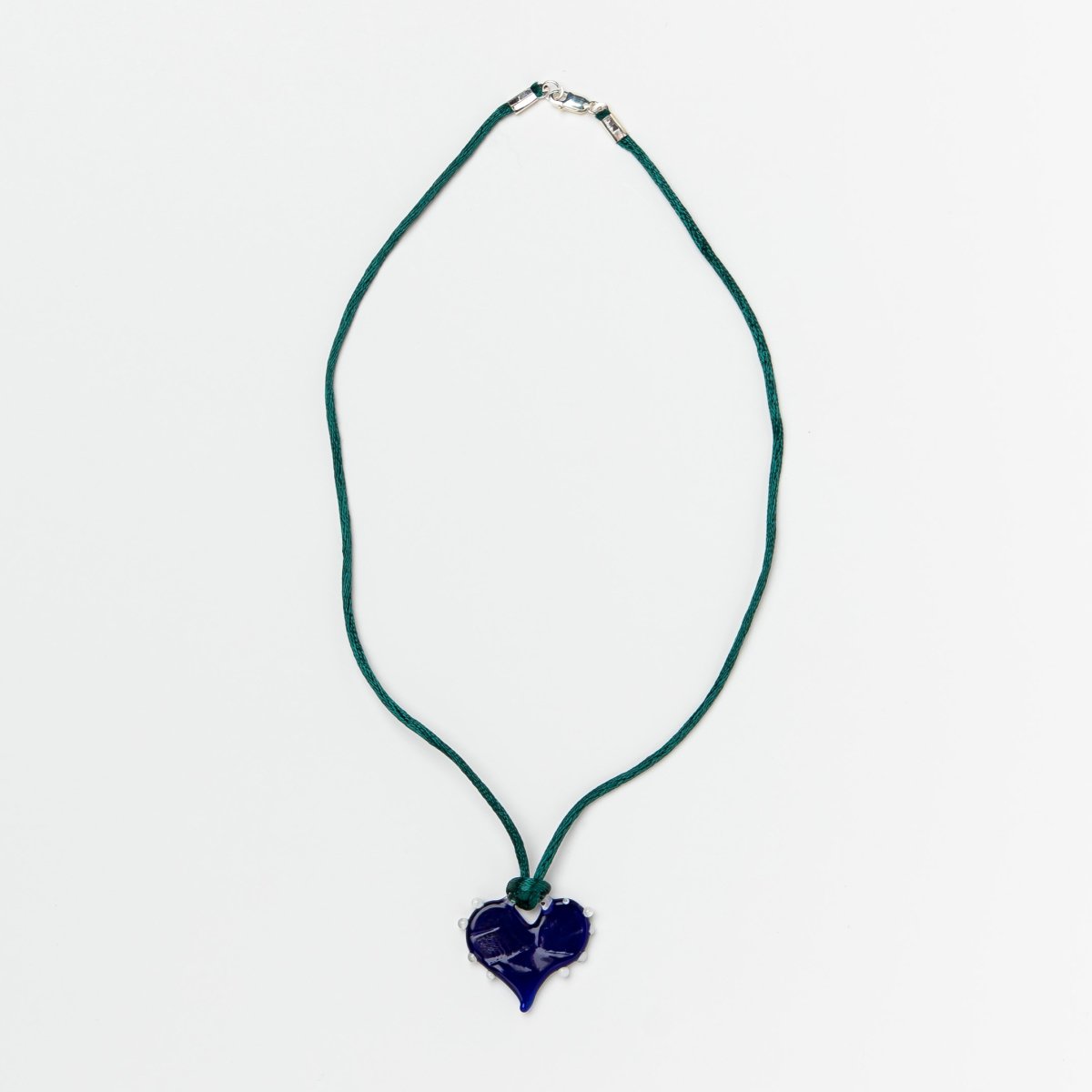 Dark blue glass heart on dark green satin